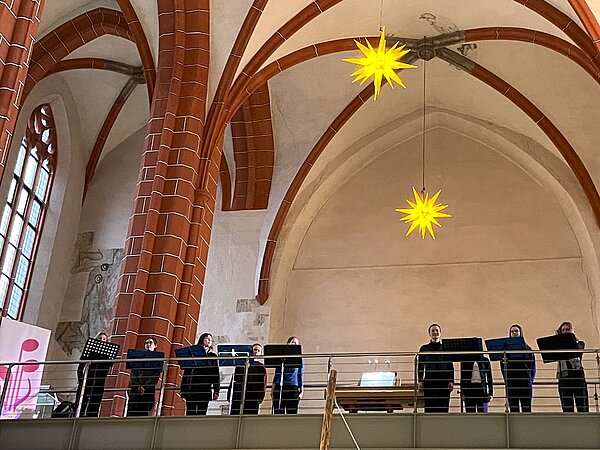 Das Gesangsensemble steht auf der Galerie im Stadtmuseum Meissen und singt.