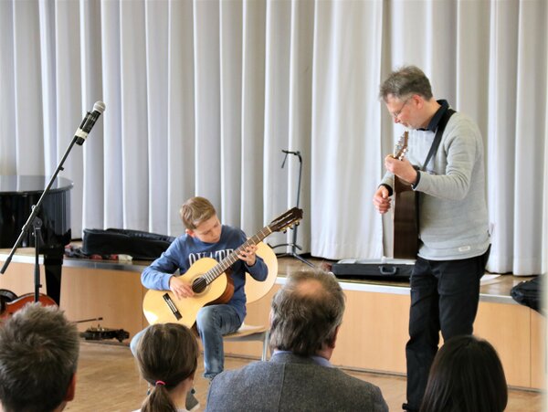 Ein Gitarrenschüler und sein Lehrer spielen zusammen ein Stück.