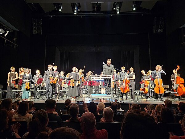 Das Jugendsinfonieorchester Radebeul steht vor applaudierendem Publikum in den Landesbühnen Sachsen auf der Bühne.