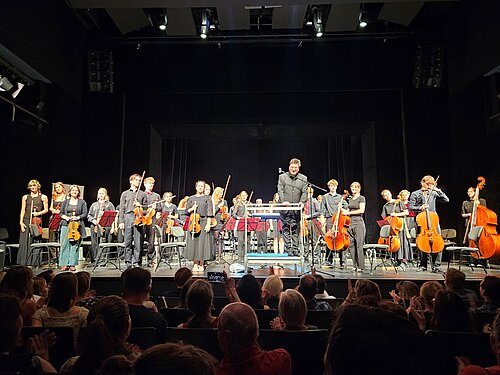 Das Jugendsinfonieorchester Radebeul steht vor applaudierendem Publikum in den Landesbühnen Sachsen auf der Bühne.