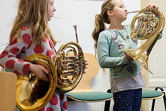 Zwei Mädchen probieren das Horn aus.