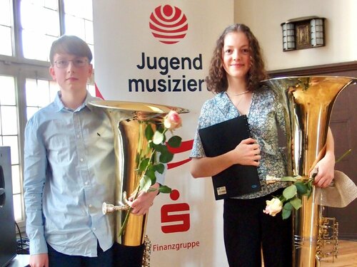 Zwei Tubaschüler stehen vor dem Aufsteller der Musikschule. Sie haben einen 1. Platz bei "jugend musiziert" erspielt.