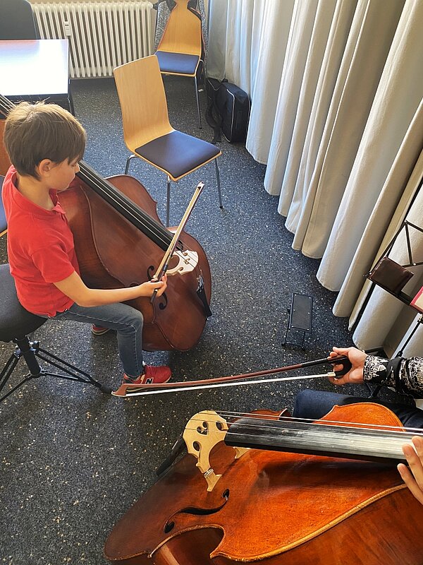 Ein Kind und ein Lehrer spielen Kontrabass.