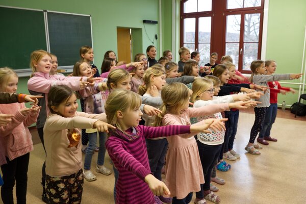 Kinder singen ein Lied und bewegen sich dazu.