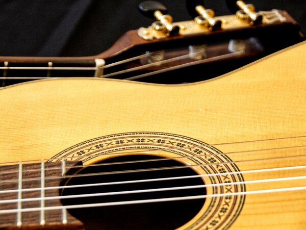 Eine Gitarre ist zweigeteilt. Zu sehen ist, entgegengesetzt, der Kopf und Korpus. 