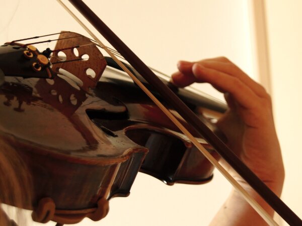Es ein Violine zu sehen, die von jemdanden gespielt wird.