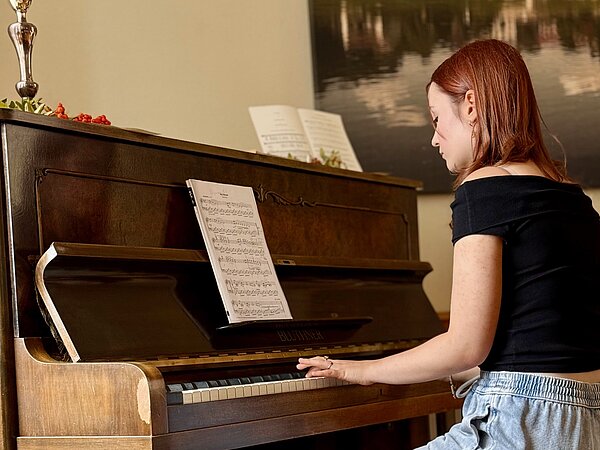 Ein Klavierschülerin sitzt am Klavier und spielt.