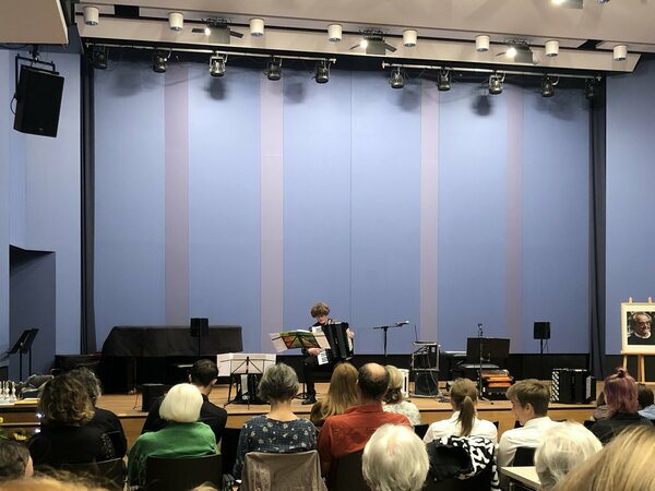 Ein Akkordeonschüler spielt auf einre Bühne vor Publikum.