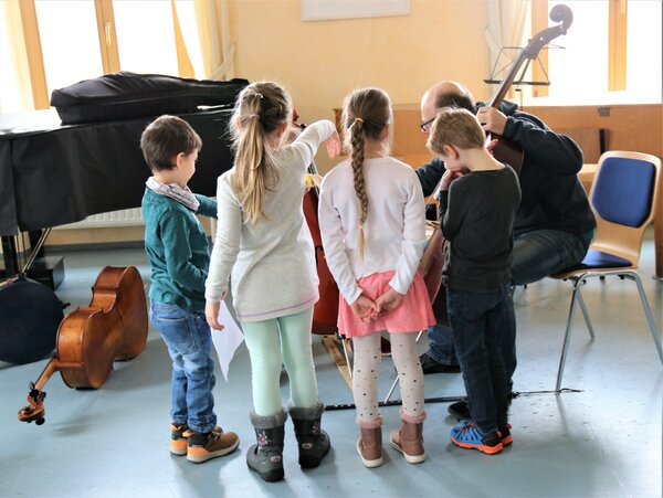 Ein paar Kinder bekommen das Cello erklärt.