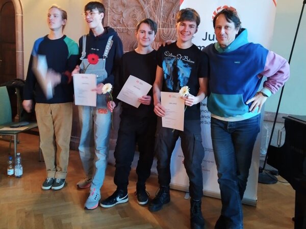 Die Band Jätal posieren vor dem Banner von Jugend jazzt mit ihrem Lehrer.