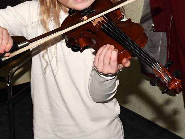 Ein Kind probiert die Geige aus.