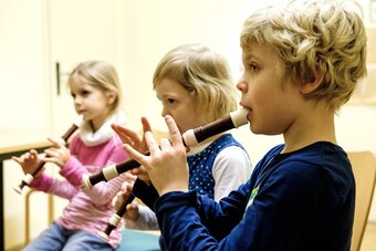 Drei Kinder der Blockflötenschule spielen zusammen.