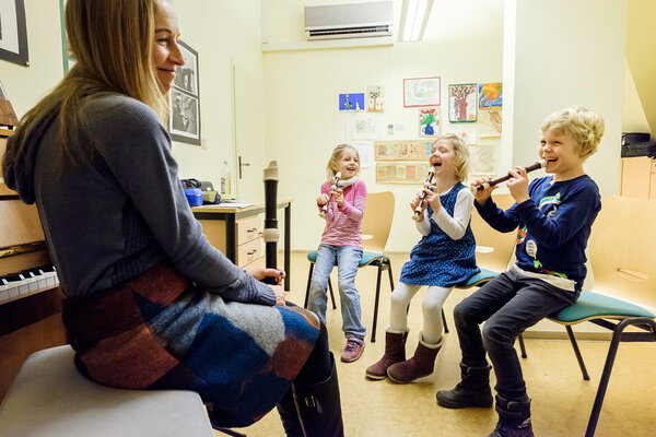 Drei Flötenschüler lachen mit ihrer Lehrerin.
