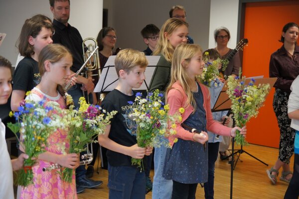 Junge Musikschüler halten Blumensträuße in ihren Händen.