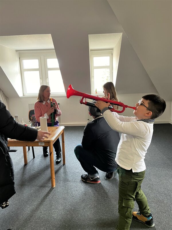 Kinder probieren Blasinstrumente aus.
