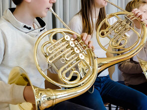 Drei Schüler spielen zusammen ihr Horn.