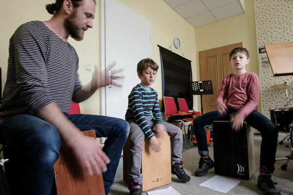 Zwei Jungen und Lehrer spielen auf ihren Cajons.