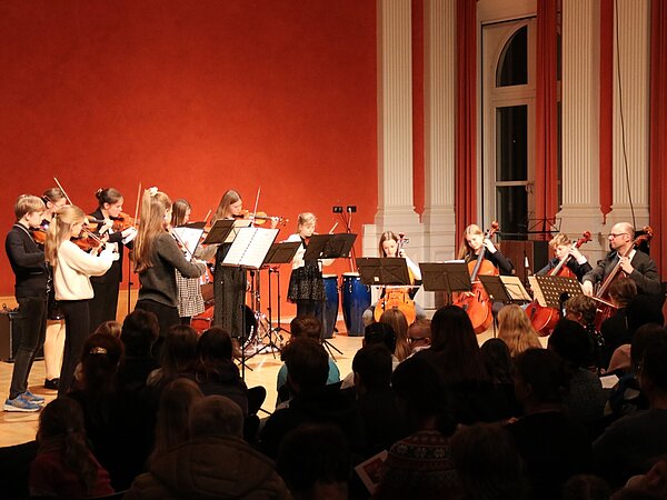 Ein Streicherensemble spielt vor großem Publikum.