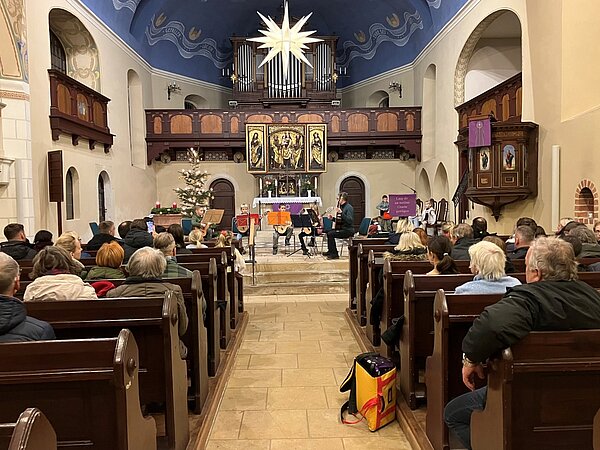 Gitarrenschüler sitzen im Altarraum und spielen vor einem zahlreichen Publikum.