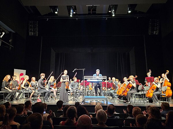 Caroline Freydank auf der Bühne mit dem Orchester vor einem begeistertem Publikum.