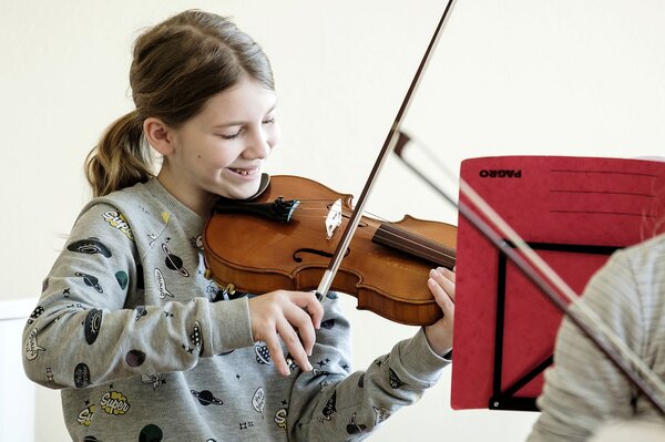 Eine Schülerin streicht fröhlich ihr Instrument.