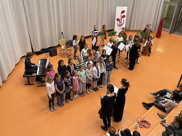 Die jungen Musikschüler der Musikschule und der junge Chor stehen auf der Bühne im Louisenstift Radebeul und spielen ein Stück vor Publikum.