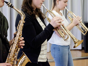 Drei Schüler, Trompete und Saxophon, spielen zusammen.