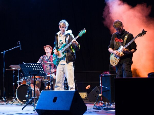Ein Band spielt auf der Bühne. Im Vordergrund sieht man einen Bassisten und einen Gitarristen.