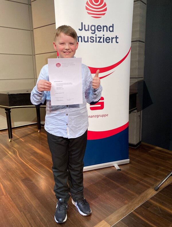 Stolz zeigt ein Schüler der am Landeswettberb "Jugend musiziert" teilgenommen hat seine Urkunde.