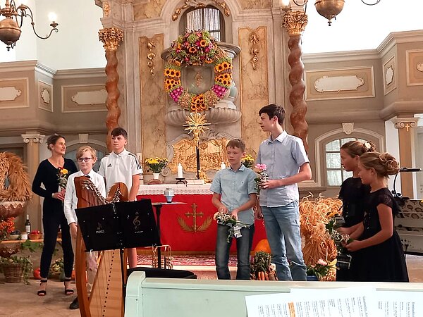 Die Musikschülerinnen und Musikschüler stehen vor dem Altar und musizieren gemeinsam.