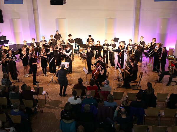 Ein Orchester spielt in der Aula des Gymnasiums Coswig vor Publikum.
