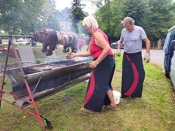 Es ist das Spanferkel zu sehen, wie es sich auf dem Spieß dreht.