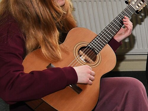 Ein Mädchen probiert die Gitarre aus.