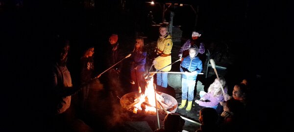 Schüler sitzen am Lagerfeuer.