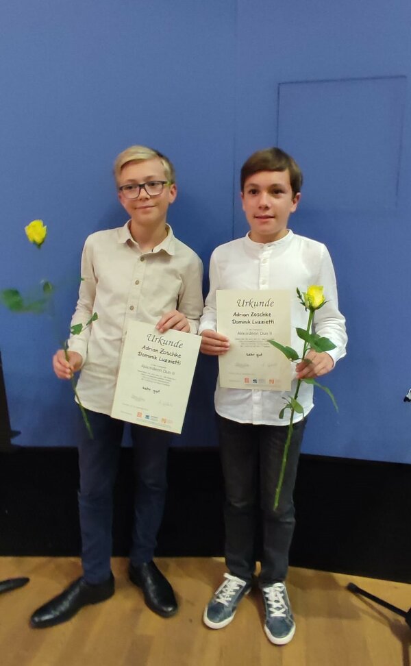 Zwei Akkordeonschüler präsentieren stolz ihre Urkunden.
