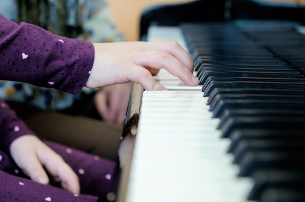 Die rechte Hand einer jungen Klavierschülerin ruht auf den Tasten.