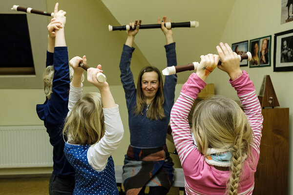 Kinder und ihre Lehrerin halten ihre Blockflöten über ihren Kopf hoch.