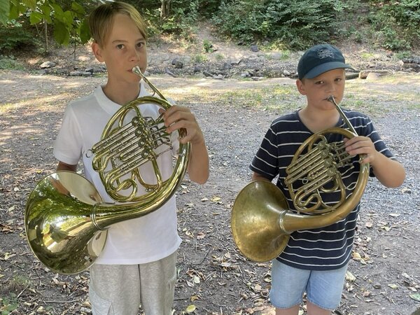 Es sind zwei Hornschüler mit ihren Instrumenten zu sehen.