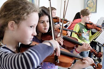 Es sind Schüler eines Streicherorchesters zu sehen.