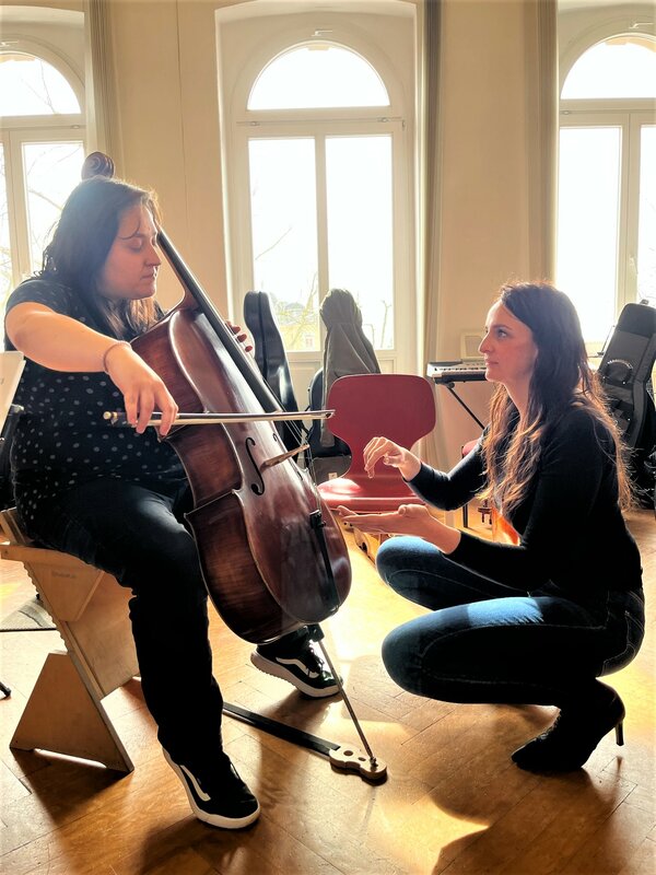 Eine Celloschülerin probiert zusammen mit ihrer Lehrerin das Instrument aus.